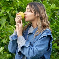 woman smelling a lemon picked from a lemon tree