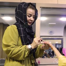 A salon owner in Kabul paints a customer's nails