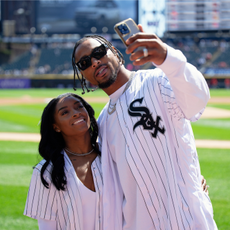 Gymnast Simone Biles and Jonathan Owens of the Chicago Bears record a video on the field before Owens threw out a first pitch before a game between the Cincinnati Reds and the Chicago White Sox at Guaranteed Rate Field on April 13, 2024 in Chicago, Illinois