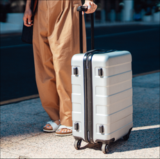 Low section of young woman walking with suitcase. City break. Business travel. Bleisure.